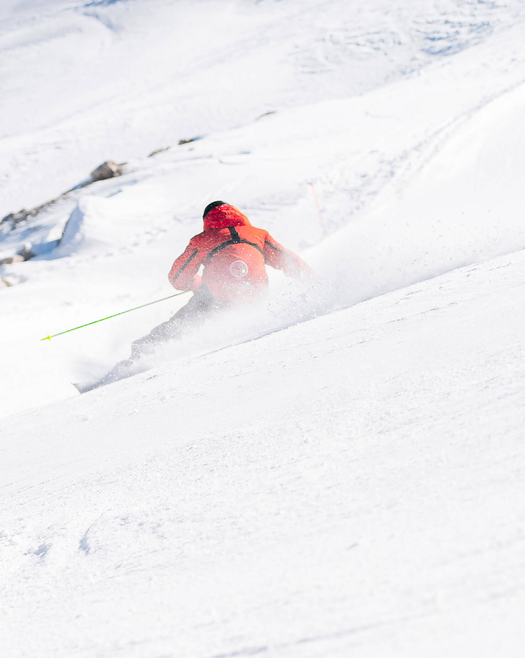 Skier in a red jacket skiing downhill in fresh white snow on a sunny day. - Scuola Sci Cortina